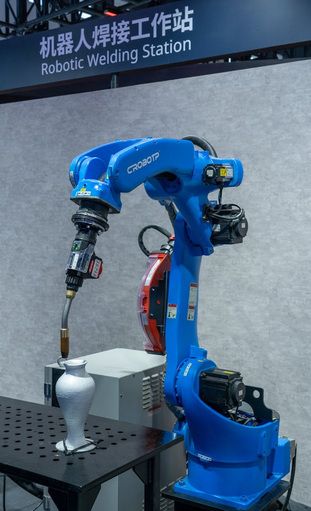 Industrial robotic welding station featuring a blue robot arm welding a metal object.